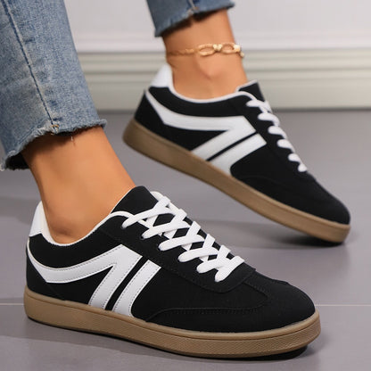Schwarze Sneaker mit weißen Streifen und brauner Sohle, getragen von Person in blauer Jeans. Modische Freizeitschuhe, ideal für Alltag und Sport.