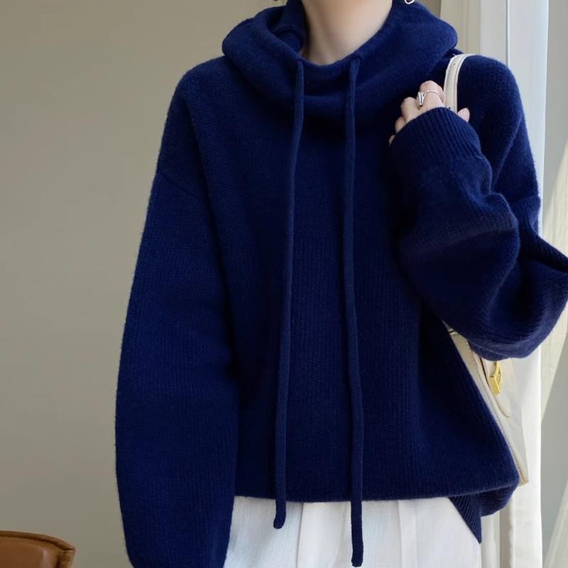 Dunkelblauer Oversize-Pullover mit Kapuze und Kordelzug, getragen von Person. Modetrend Herbst/Winter, gemütlicher Strick, lässiger Stil.