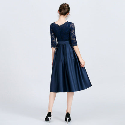 Frau in elegantem, knielangem, dunkelblauem Abendkleid mit Spitzenärmeln, Rückansicht. Perfekt für formelle Anlässe und Abendveranstaltungen.