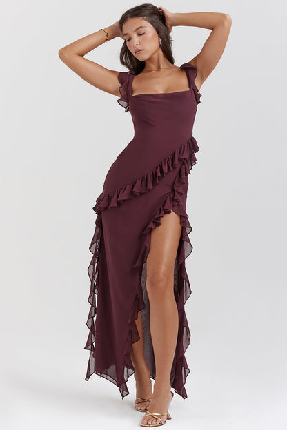 Frau in elegantem, weinrotem Abendkleid mit Rüschen, posiert selbstbewusst. Perfektes Outfit für formelle Anlässe und Abendveranstaltungen.