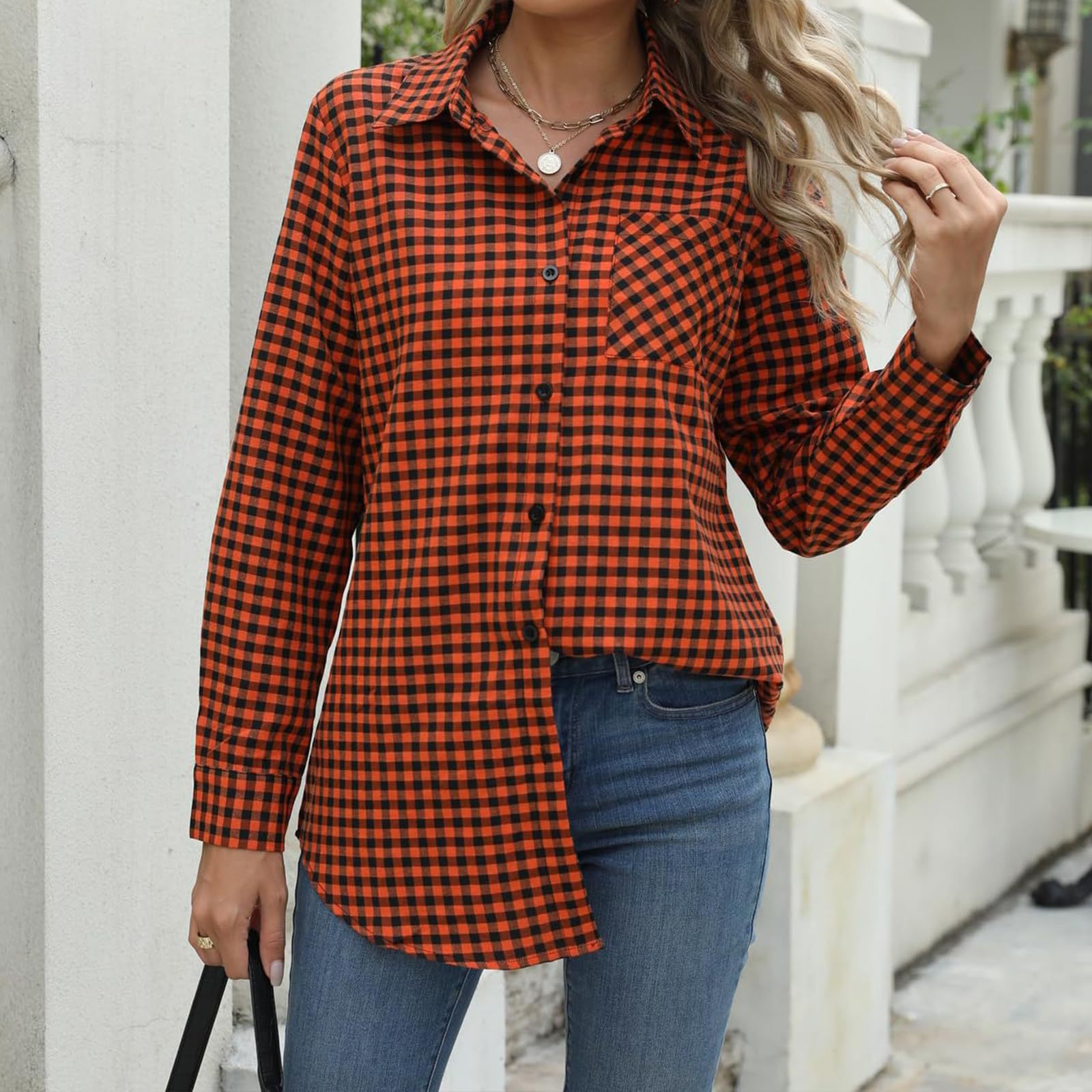 Frau in kariertem Hemd, asymmetrisch geschnitten, kombiniert mit blauen Jeans. Modetrend, Herbstmode, lässiger Stil, Outdoor-Fotografie.