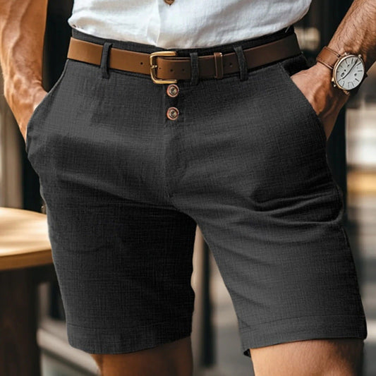 Mann in eleganter schwarzer Shorts mit braunem Gürtel und weißem Hemd, trägt eine Armbanduhr. Sommermode, Herrenbekleidung, stilvoller Look.