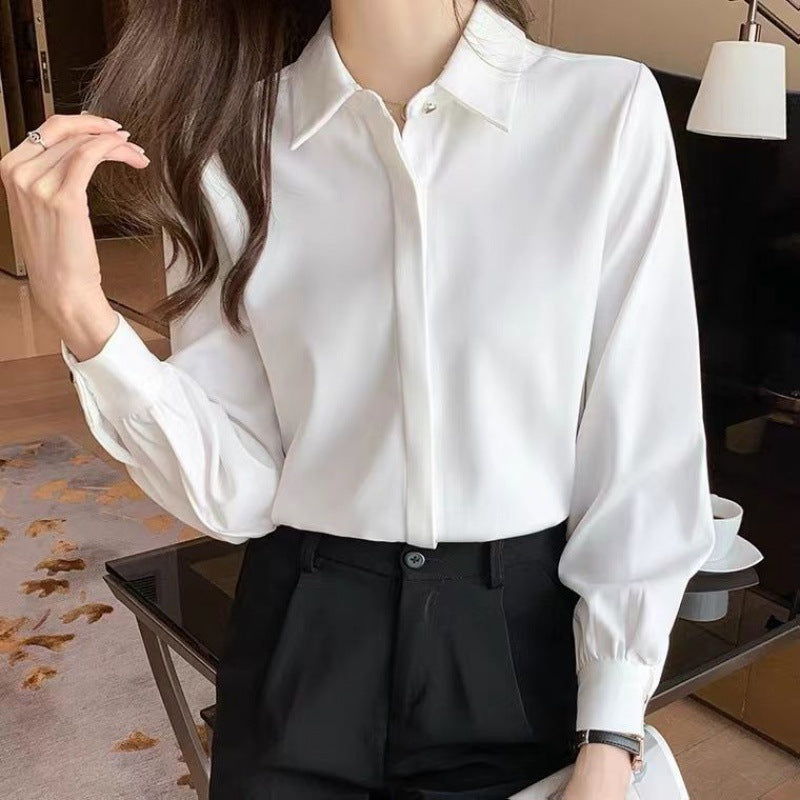 Elegante Frau in weißer Bluse und schwarzer Hose, steht in modernem Wohnzimmer. Stilvolle Mode, Business-Look, zeitlose Eleganz.