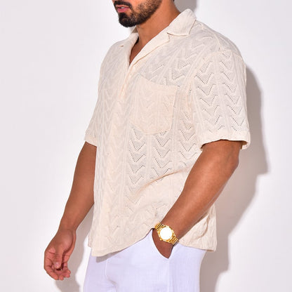 Beiger Herren-Strickhemd mit Chevron-Muster, kurzärmelig, kombiniert mit weißer Hose. Perfekt für Sommermode und lässige Outfits.