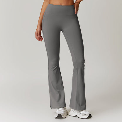 Frau in grauer Yoga-Hose und weißen Turnschuhen, stehend vor neutralem Hintergrund. Sportbekleidung, Fitnessmode, bequeme Leggings.