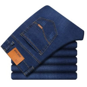 Gestapelte blaue Jeans mit Gesäßtasche und braunem Etikett, klassische Denim-Hose, modische Herrenbekleidung, hochwertige Jeansmode.