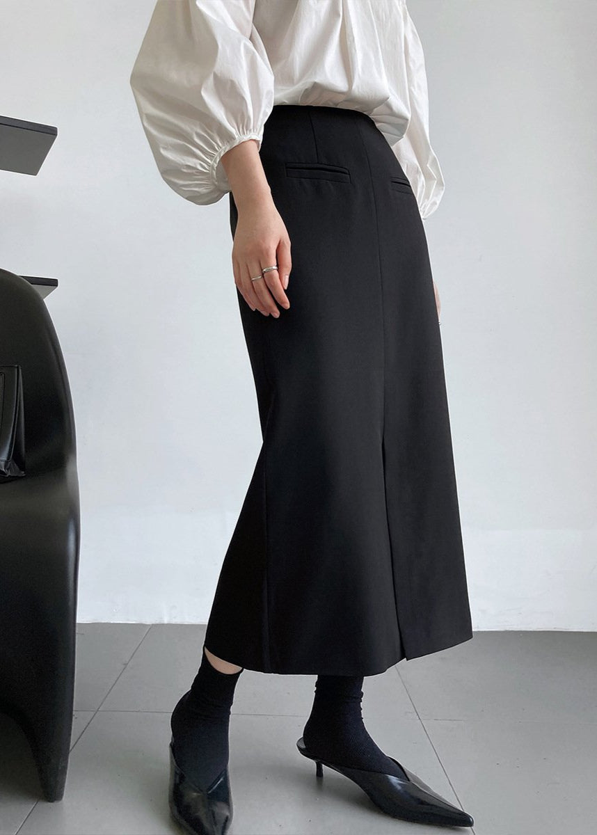 Eleganter schwarzer Midirock, kombiniert mit weißer Bluse und schwarzen Absatzschuhen. Modischer Business-Look für Damen.