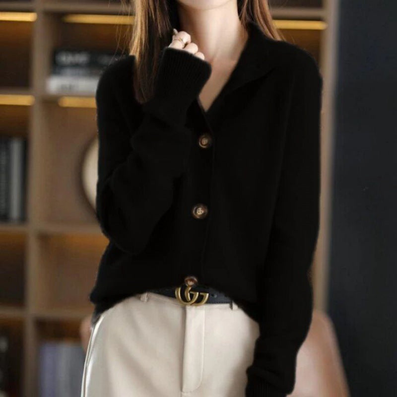 Frau in schwarzem Cardigan mit Knöpfen, beige Hose, modisch, elegant, Innenraum, Bücherregal im Hintergrund, stilvolle Herbstmode.