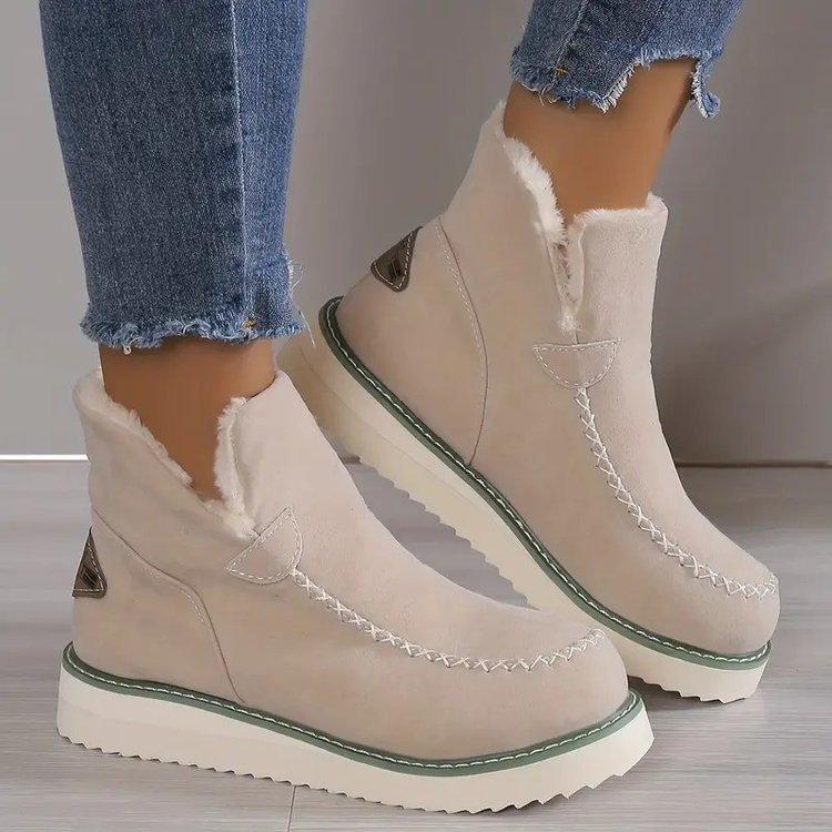 Beige Damen-Winterstiefel mit Kunstfellfutter, dicker Sohle und Ziernähten, getragen mit blauen Jeans. Ideal für kaltes Wetter und modische Outfits.
