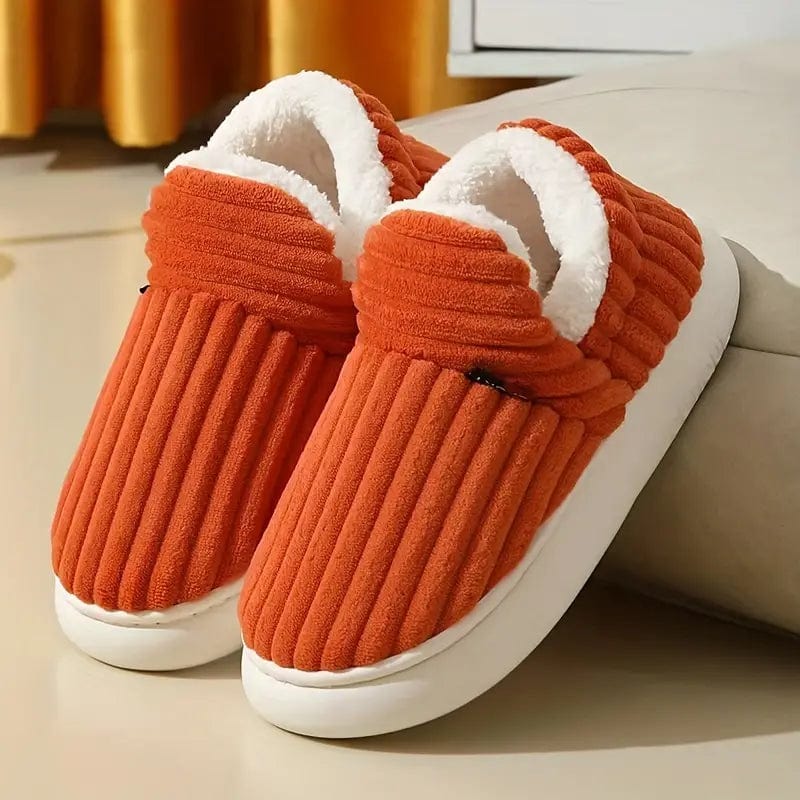 Orange Hausschuhe mit weißem Plüschfutter, gerippte Textur, auf hellem Hintergrund. Bequeme, warme Pantoffeln für den Winter.