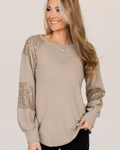 Frau trägt beige Pullover mit goldenen Pailletten an Ärmeln, lächelt, blonde Haare. Modetrend, Damenmode, eleganter Freizeitlook.