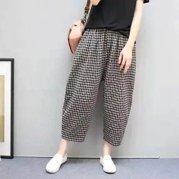 Frau in karierten Hosen und schwarzem T-Shirt, trägt weiße Schuhe und rosa Tasche. Modetrend, lässiger Stil, Damenbekleidung.
