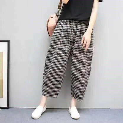 Frau in karierten Hosen und schwarzem T-Shirt, trägt weiße Schuhe und rosa Tasche. Modetrend, lässiger Stil, Damenbekleidung.