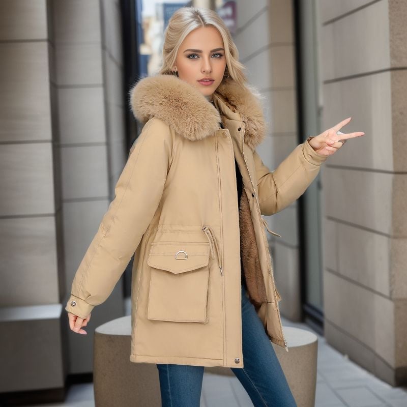 Blonde Frau in beiger Winterjacke mit Fellkragen, posiert in urbaner Umgebung. Modische Damenbekleidung, Wintermantel, Streetstyle.