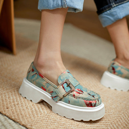 Damen-Loafer mit floralem Muster, dicker weißer Sohle und goldener Schnalle, getragen auf Teppichboden. Modische Schuhe, bequeme Damenmode.