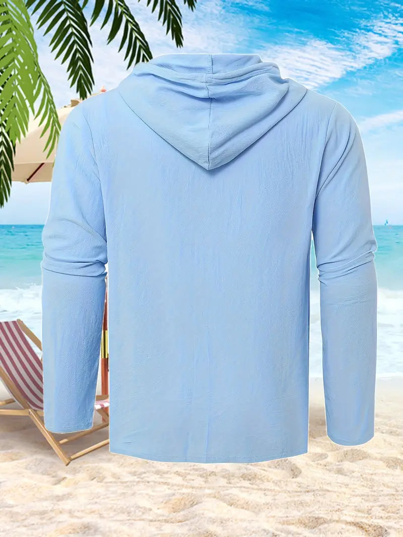 Hellblaues Kapuzen-Shirt am Strand, umgeben von Palmen und Liegestuhl, ideal für Sommermode und Strandbekleidung.