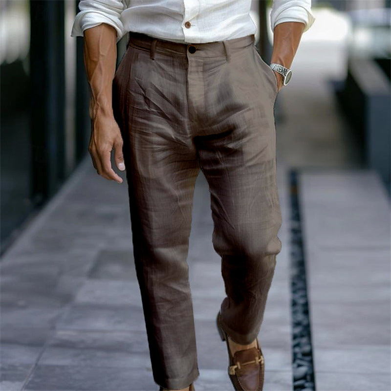 Eleganter Mann in brauner Leinenhose und weißem Hemd, gehend auf städtischem Gehweg. Stilvolle Mode, Herrenbekleidung, urbane Eleganz.
