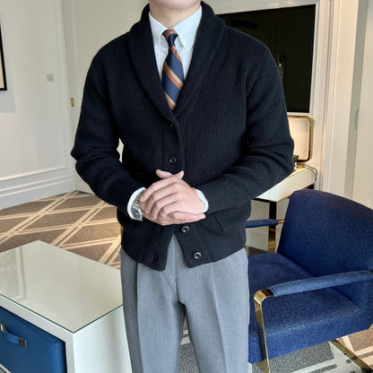 Mann im eleganten schwarzen Cardigan mit Krawatte und grauer Hose, steht in modernem Büro. Businessmode, Herrenbekleidung, stilvoller Look.