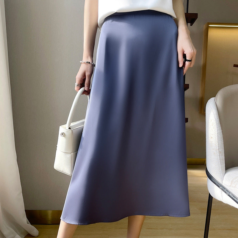 Frau in elegantem, langem, blauem Satinrock, hält weiße Handtasche. Modetrend, Damenmode, stilvoller Look, schickes Outfit, zeitlose Eleganz.