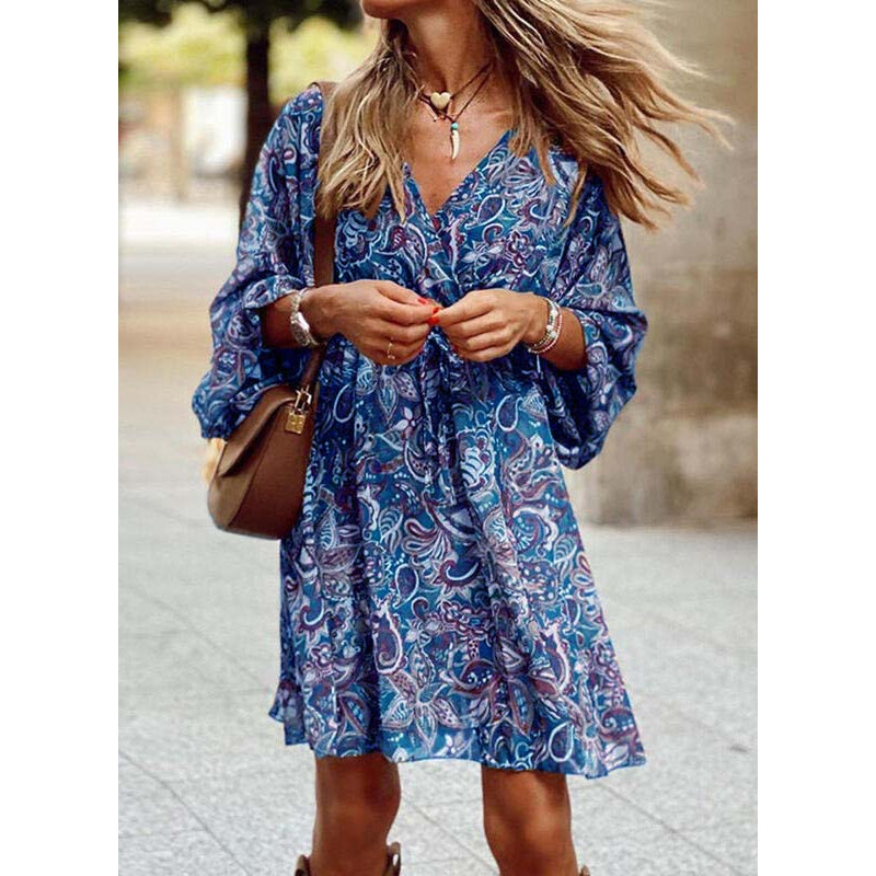 Frau in blauem Boho-Kleid mit Paisley-Muster, brauner Umhängetasche und Schmuck, spaziert draußen. Modetrend, Sommerkleid, lässiger Stil.