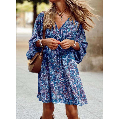 Frau in blauem Boho-Kleid mit Paisley-Muster, brauner Umhängetasche und Schmuck, spaziert draußen. Modetrend, Sommerkleid, lässiger Stil.