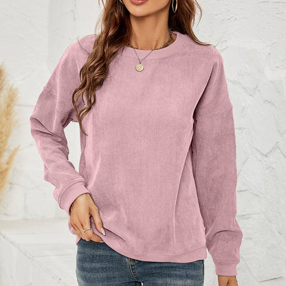 Frau in rosa Cord-Sweatshirt, lässiger Stil, kombiniert mit blauer Jeans. Modetrend Herbst, bequeme Damenbekleidung, Freizeitlook.
