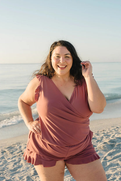 Frau in rosa Strandkleidung lächelt am Meer, sonniger Tag, entspannter Strandspaziergang, Sommermode, Urlaub am Meer, Freizeitkleidung.