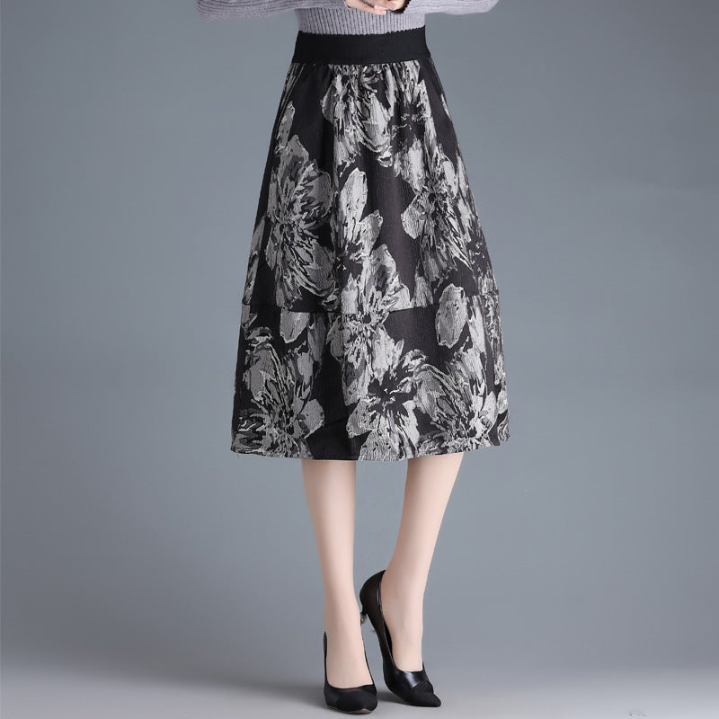 Damenrock mit floralem Muster in Schwarz-Weiß, knielang, kombiniert mit schwarzen Pumps. Elegante Mode für Herbst und Winter.