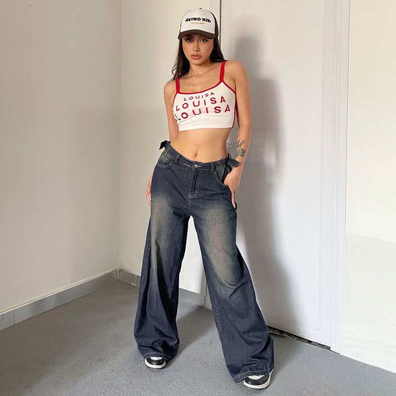 Junge Frau in weitem Jeans und Crop-Top posiert in modernem Raum, trägt Retro-Kappe. Modetrend, lässiger Stil, Streetwear, jugendliche Mode.