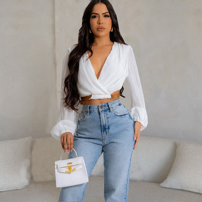 Frau in weißer Bluse und blauer Jeans hält weiße Handtasche. Modetrend, elegante Damenmode, stilvolles Outfit, moderne Accessoires.