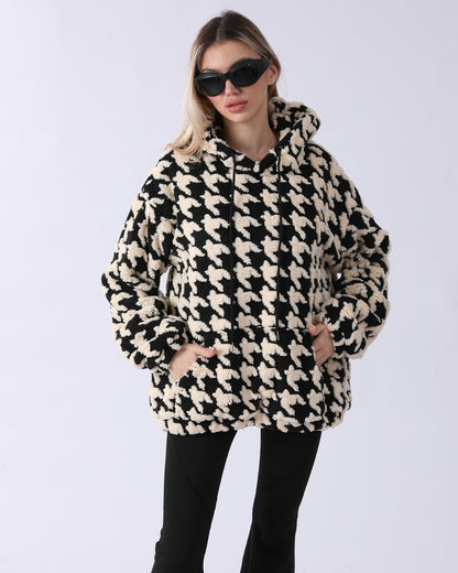 Frau in schwarz-weißem Hahnentritt-Muster Hoodie, trägt Sonnenbrille. Modetrend, Wintermode, stilvoller Look, gemütlicher Pullover.