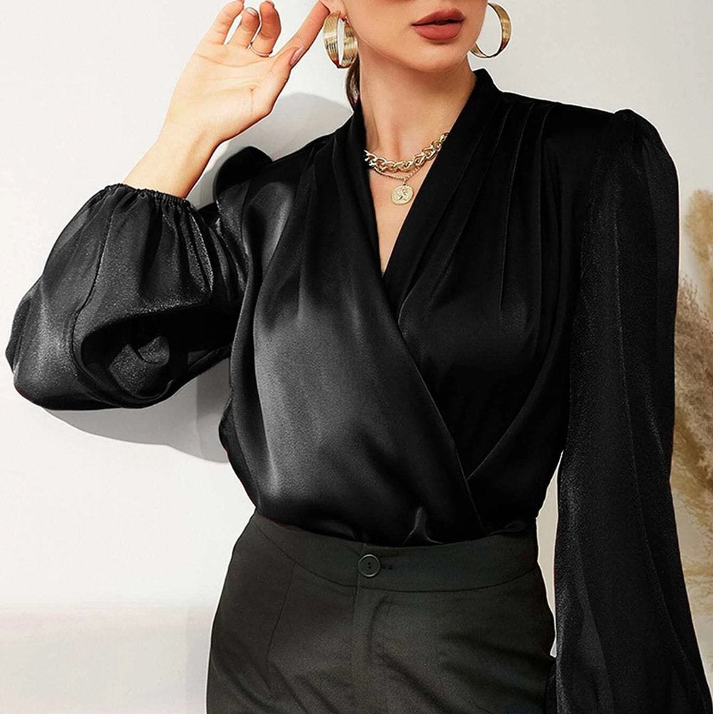 Frau in eleganter schwarzer Bluse mit langen Ärmeln und goldenen Accessoires, modischer Look, stilvolle Damenmode, Business-Outfit.