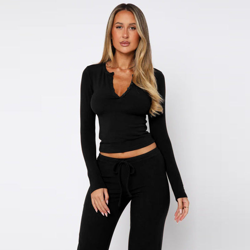 Eine Frau in schwarzem, langärmligem Oberteil und Hose vor weißem Hintergrund. Mode, Damenbekleidung, eleganter Look.