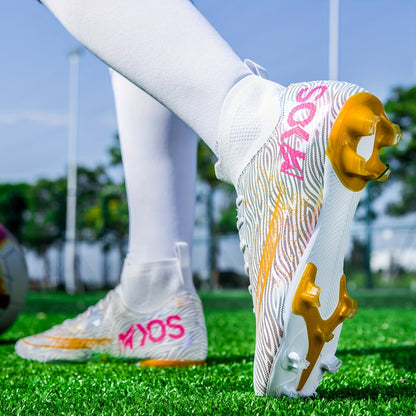 Weiße Fußballschuhe mit goldenen Stollen und pinkem Schriftzug auf grünem Rasen, getragen von Person in weißen Socken. Ideal für Fußballtraining.