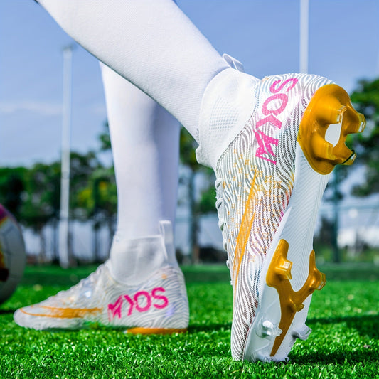 Weiße Fußballschuhe mit goldenen Stollen und pinkem Schriftzug auf grünem Rasen, getragen von Person in weißen Socken. Ideal für Fußballtraining.