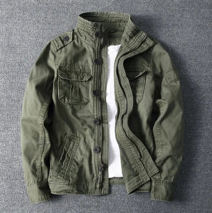 Olivgrüne Herrenjacke mit Stehkragen, Knopfleiste und mehreren Taschen auf grauem Hintergrund. Modische Outdoor-Bekleidung, lässiger Stil.