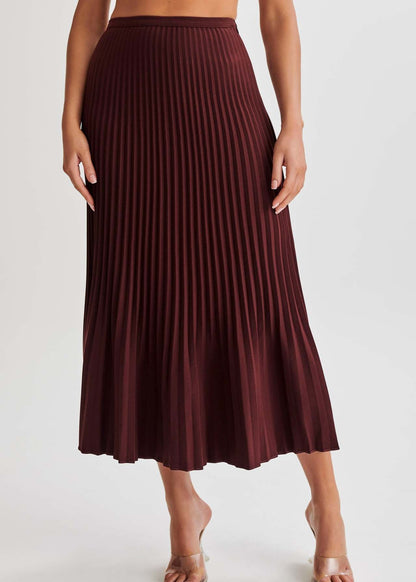 Frau trägt langen, weinroten Plisseerock, elegant und modisch, ideal für Herbstmode. Perfekt kombinierbar mit verschiedenen Oberteilen und Schuhen.