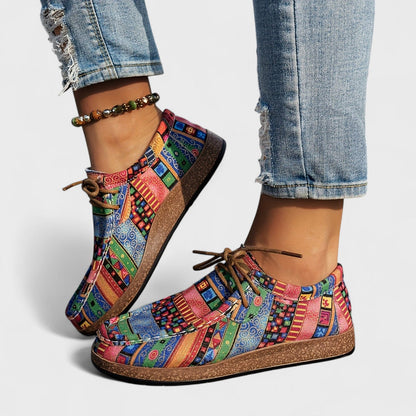 Bunte Damen-Sneaker mit Patchwork-Muster, kombiniert mit zerrissenen Jeans und einem Perlenarmband. Modische Freizeitschuhe für den Alltag.