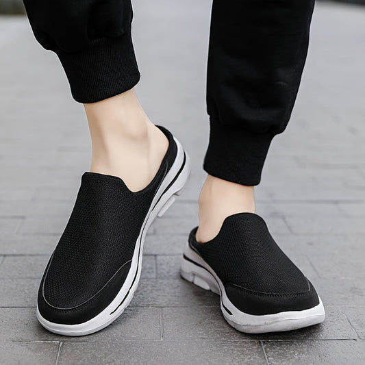 Schwarze Slip-On-Sneaker auf grauem Gehweg, getragen von Person in schwarzer Hose. Bequeme Freizeitschuhe, atmungsaktiv, ideal für Alltag und Sport.