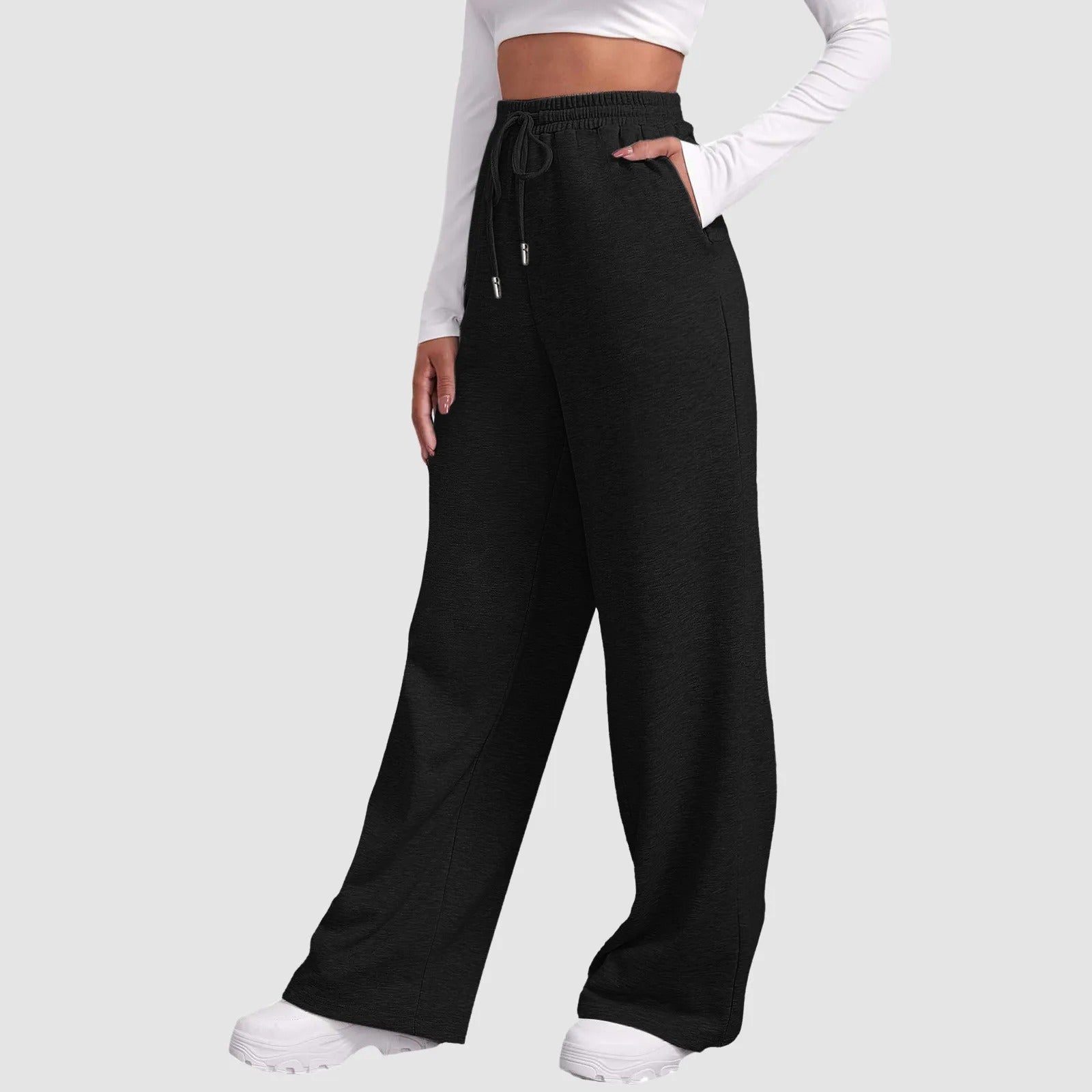 Frau in schwarzer Jogginghose und weißem Crop-Top, modische Freizeitkleidung, bequeme weite Passform, ideal für Sport und Alltag.