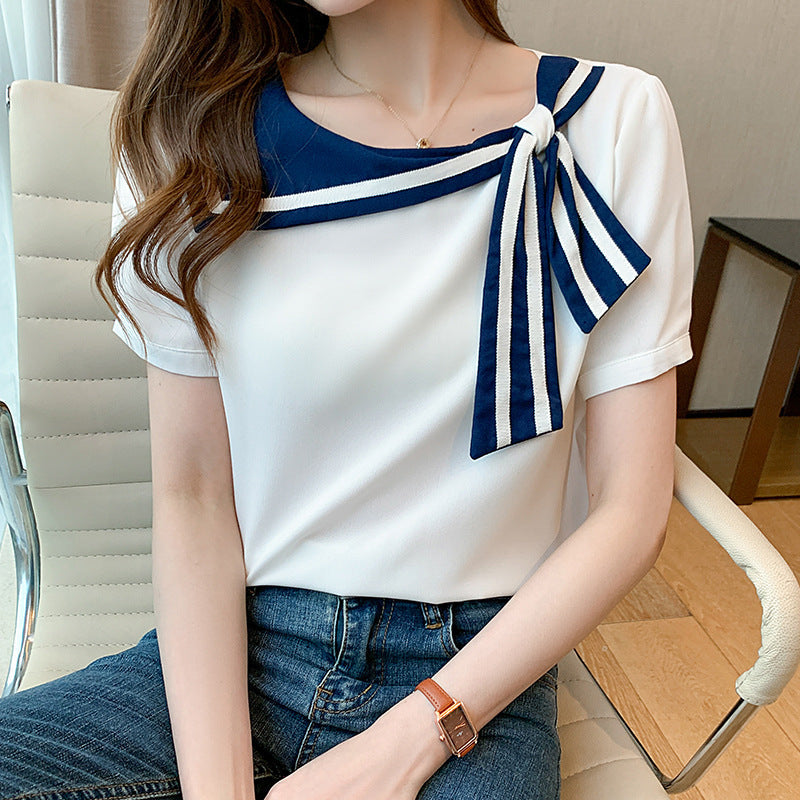 Frau in weißem T-Shirt mit blau-weißem Schleifendetail, sitzt auf einem Bürostuhl. Modetrend, elegantes Design, Freizeitkleidung.