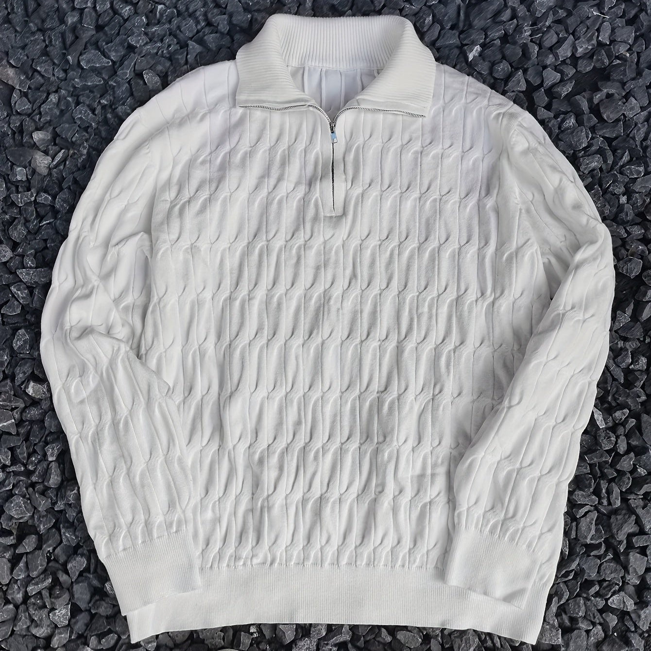 Weißer Strickpullover mit Reißverschluss auf dunklem Kies. Modischer Herrenpullover, ideal für Herbst und Winter. Elegantes Strickmuster.