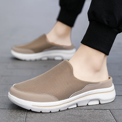 Beige Herren-Sneaker mit weißer Sohle, atmungsaktives Mesh-Obermaterial, ideal für Freizeit und Sport, getragen auf grauem Pflaster.
