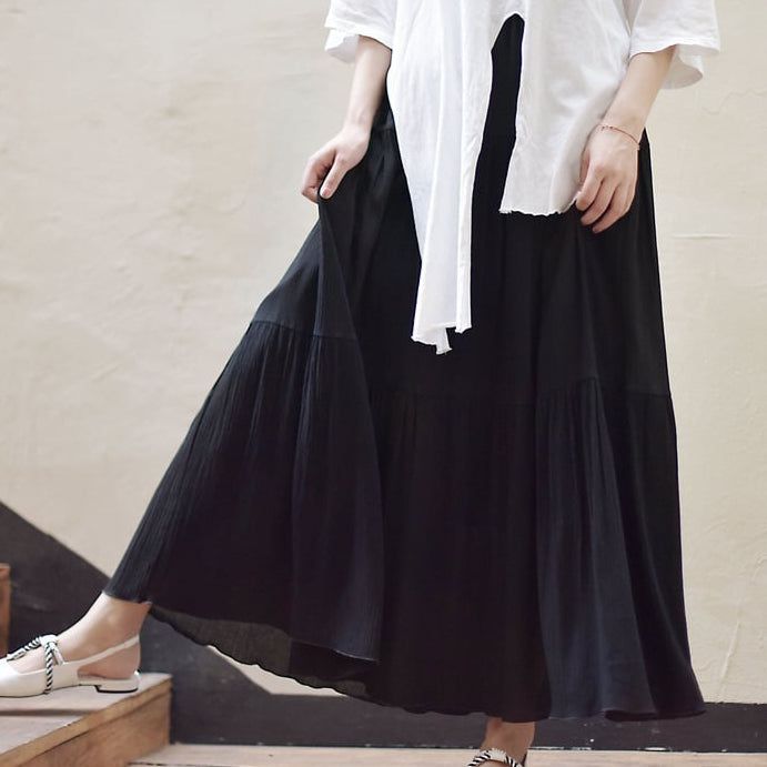 Frau in weißem Oberteil und langem schwarzem Rock auf Treppe. Modetrend, Damenmode, eleganter Look, Sommeroutfit, stilvolle Kleidung.