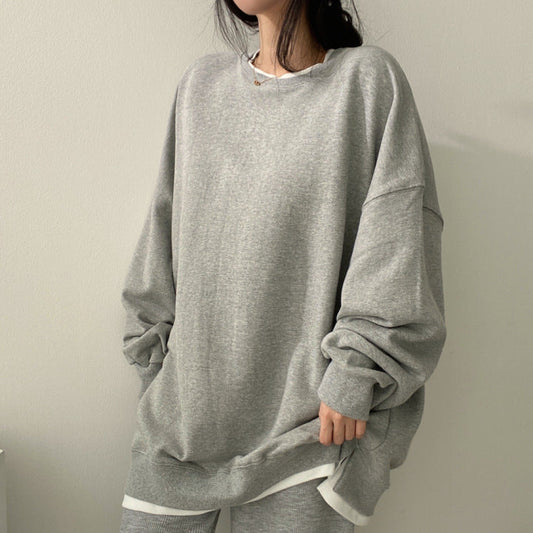 Graues Oversize-Sweatshirt, lässig getragen von Frau. Modetrend, bequeme Freizeitkleidung, minimalistisch, gemütlicher Look.