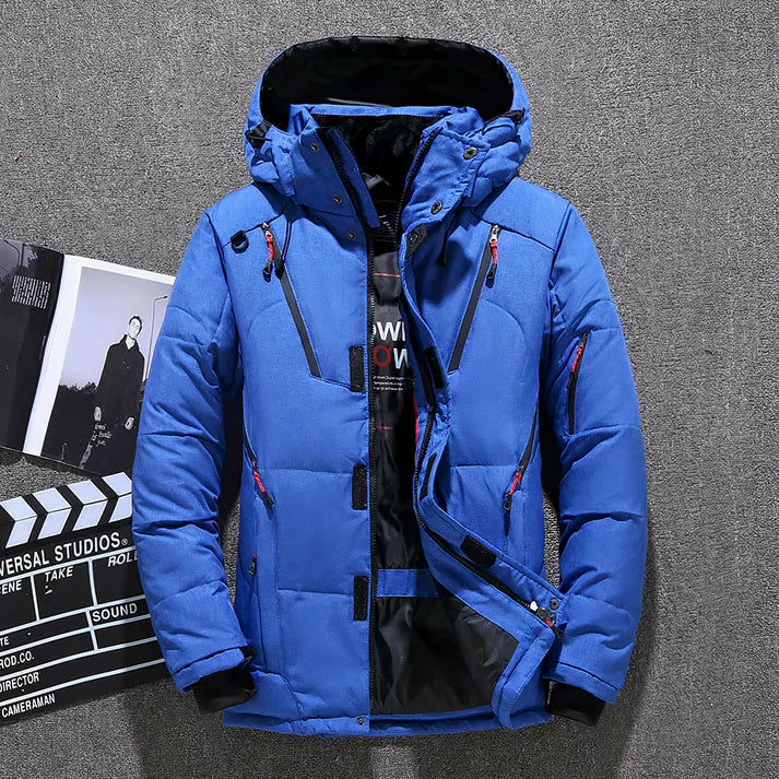 Blaue Winterjacke mit Kapuze, Reißverschlüssen und Taschen, ideal für Outdoor-Aktivitäten. Stilvoll und warm, perfekt für kalte Temperaturen.