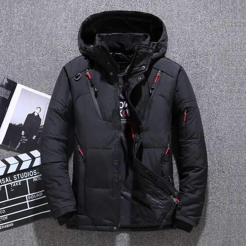 Schwarze Winterjacke mit Kapuze, Reißverschlüssen und roten Akzenten, ideal für kaltes Wetter. Perfekt für Outdoor-Aktivitäten und modischen Stil.