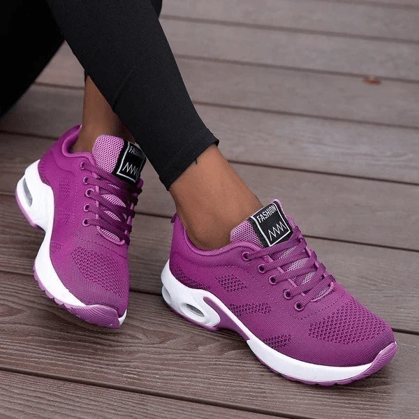 Lila Damen-Sneaker auf Holzterrasse, atmungsaktives Mesh-Design, weiße Sohle, sportlich, modisch, ideal für Freizeit und Fitness.