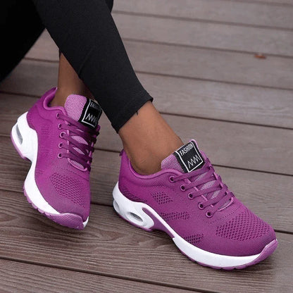 Lila Damen-Sneaker auf Holzterrasse, atmungsaktives Mesh-Design, weiße Sohle, sportlich, modisch, ideal für Freizeit und Fitness.