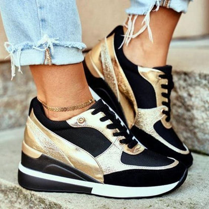Schwarze und goldene Sneaker mit Keilabsatz, getragen mit zerrissenen Jeans. Modische Damen-Sportschuhe, trendiges Design, urbaner Stil.